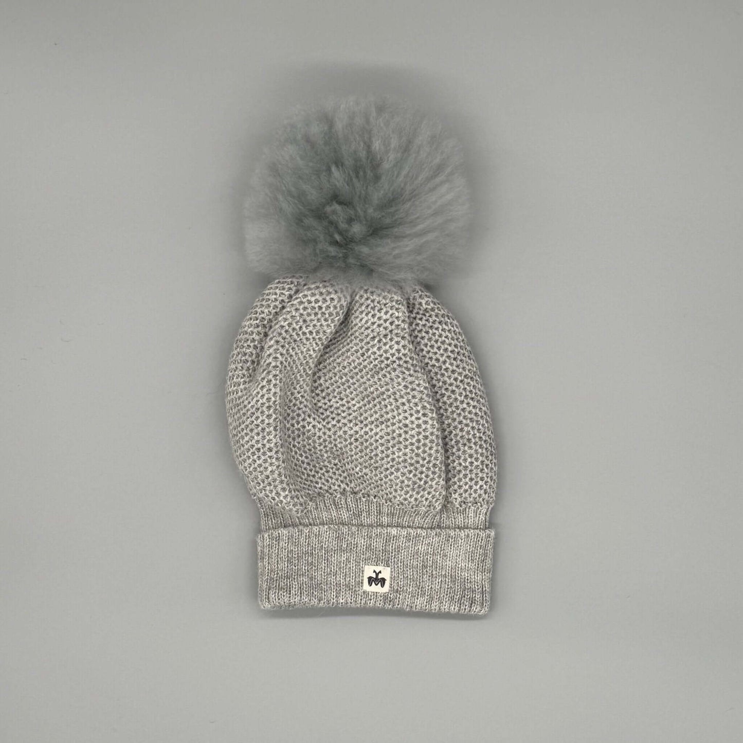 Alpakamütze mit Bommel aus 100 % Alpaka Echtfell in Grau mit feinem Strickmuster und stylishen Bommel.