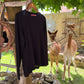 Schwarzer Alpaka Pullover Damen aus 100% Baby-Alpakawolle hinter Alpakas im Freien.
