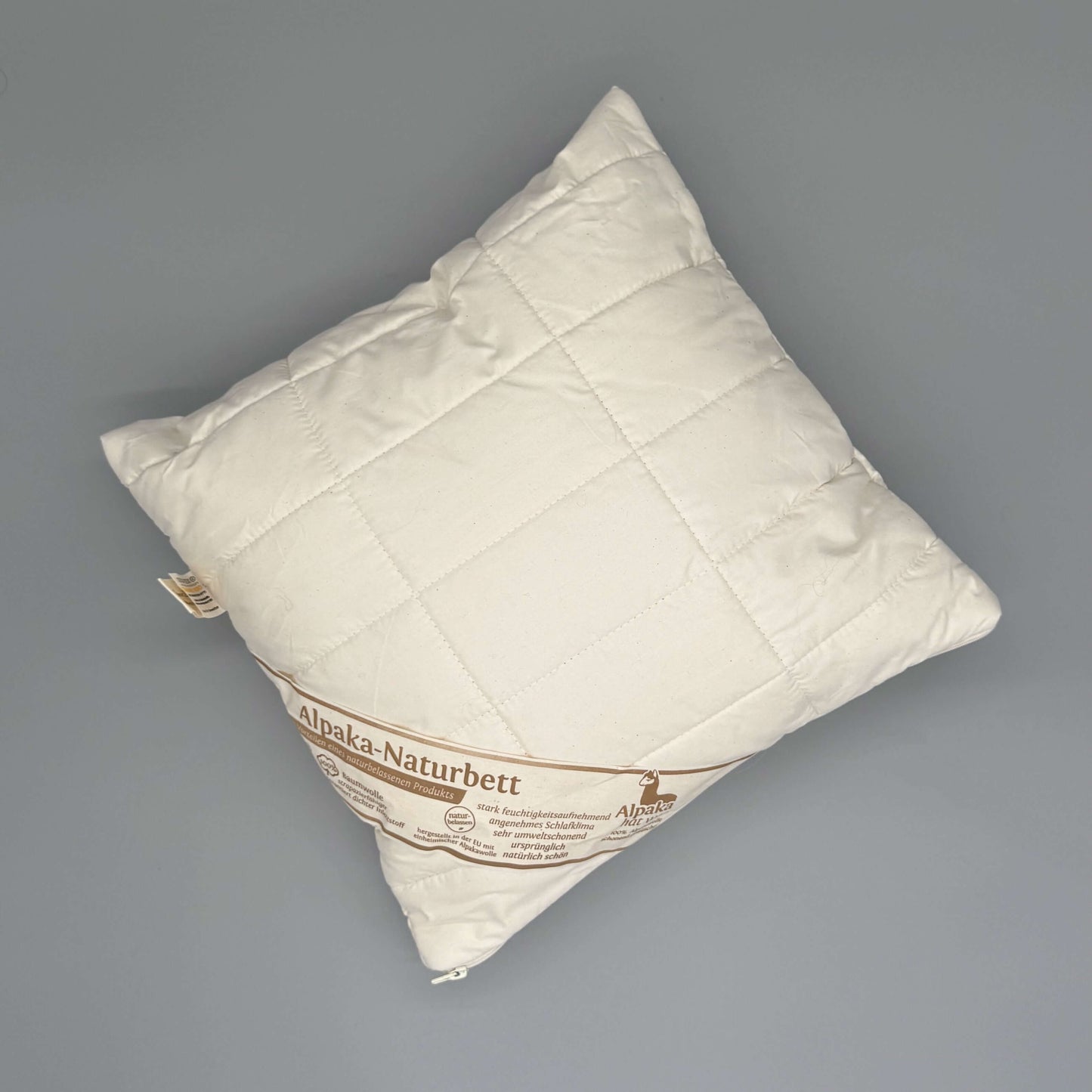 Alpaka Kissen 40x40 – Handgemachtes Naturkissen aus 100% Alpakavlies auf grauem Hintergrund.