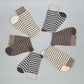 Socken aus Alpaka Wolle im Ringelmuster in Braun und Grau für Damen & Herren auf grauem Hintergrund.