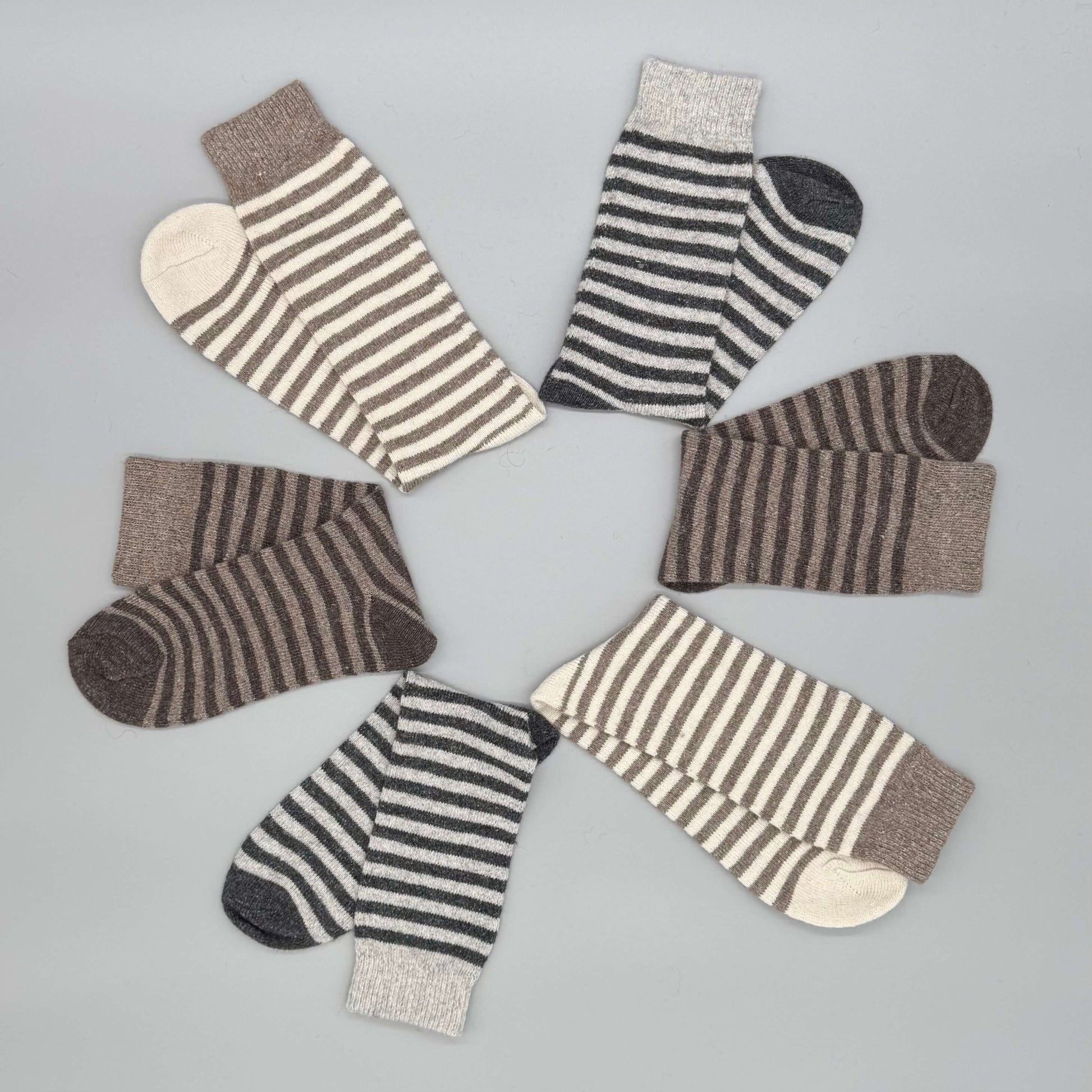 Socken aus Alpaka Wolle im Ringelmuster in Braun und Grau für Damen & Herren auf grauem Hintergrund.