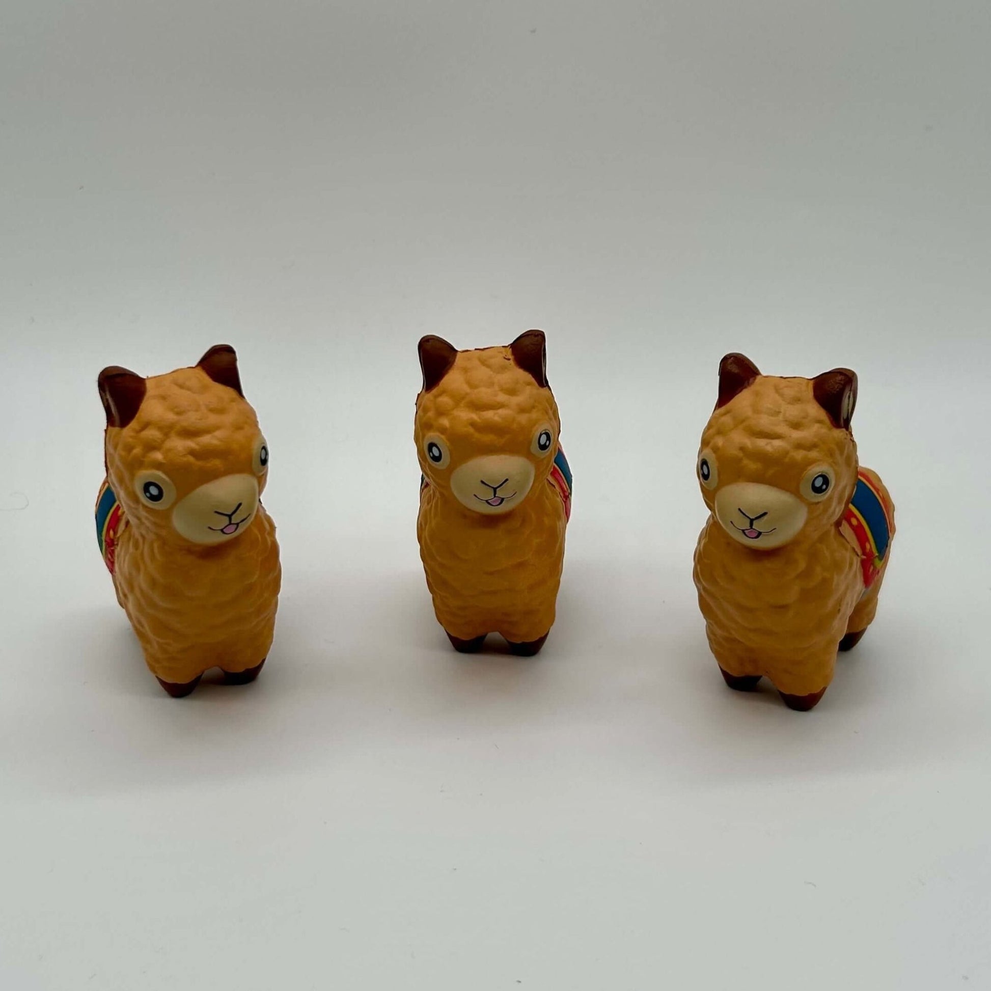 Drei mehrfarbige Alpaka Stressball Figuren auf weißem Hintergrund, ideal zum Kneten und Stressabbau.