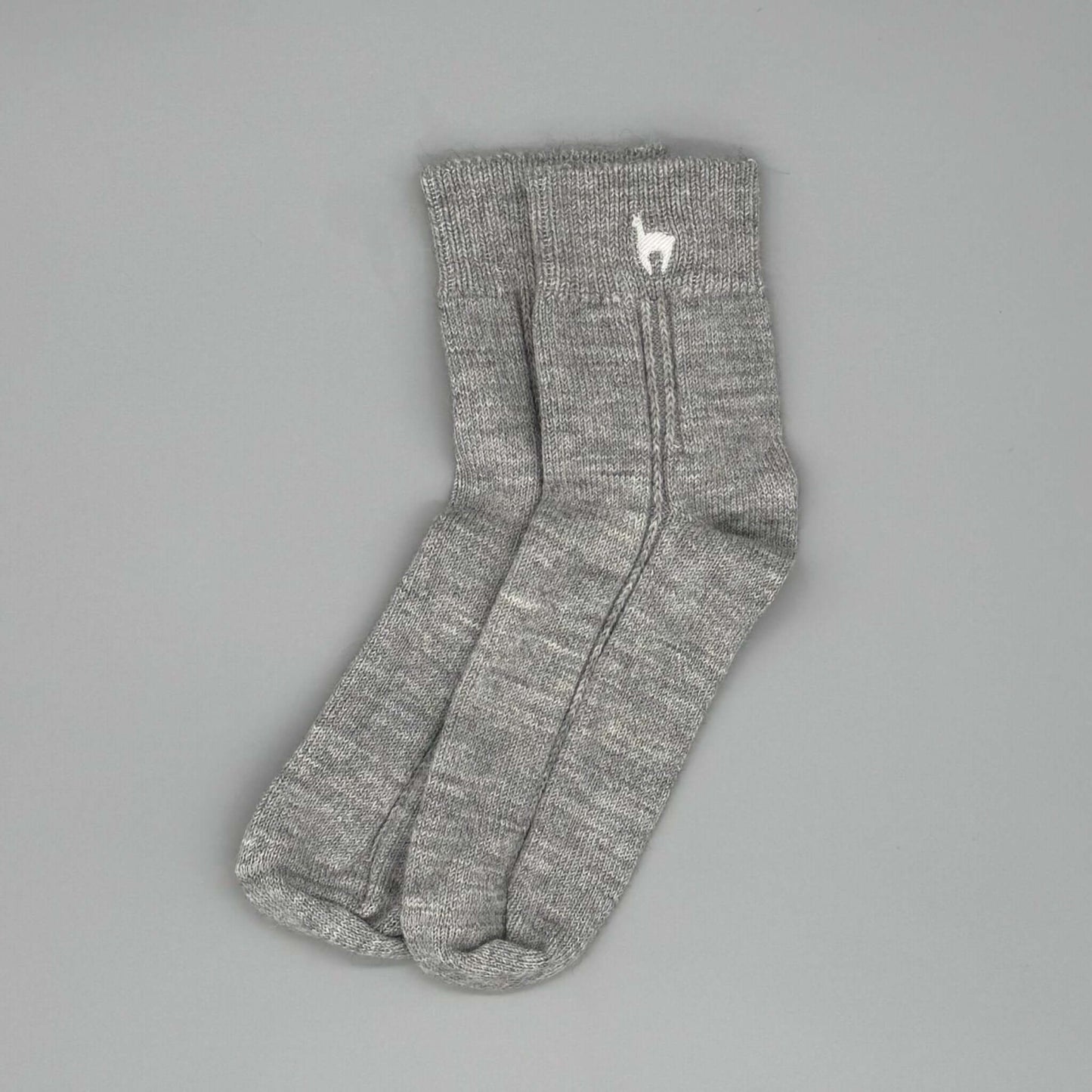 Bio Alpaka Socken aus grauer Alpakawolle mit Alpaka-Stickerei auf dem Bündchen.